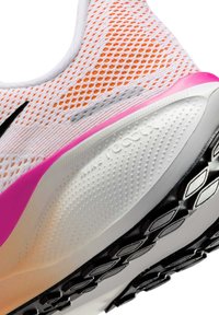 Białe siatkowe buty sportowe z pomarańczowymi akcentami, z różowym zapiętkiem, teksturowaną podeszwą i logo "Nike React". Krzywolinowy, aerodynamiczny design.