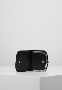 Portefeuille en cuir noir avec fermeture à pince, texture lisse et design épuré. Intérieur avec des compartiments pour cartes et billets.