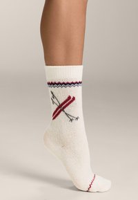 Bijele pamučne čarape s motivom skijanja u crvenoj i sivoj boji, s ukrasnim crveno-plavim rebrastim rubom na vrhu.