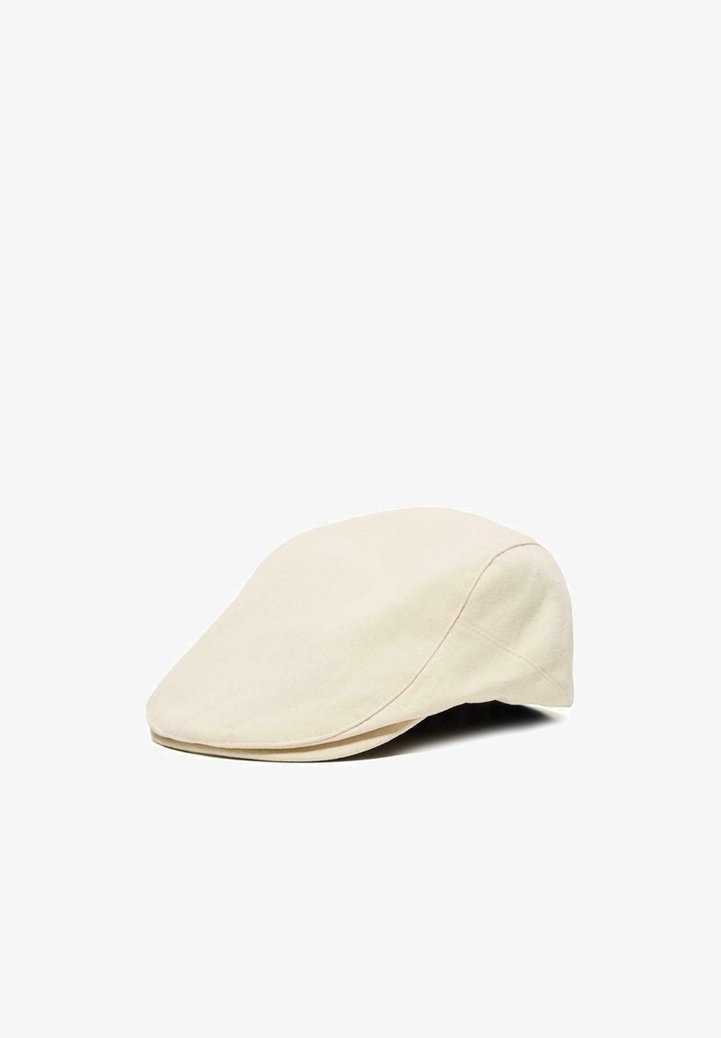 Cappello piatto beige con un design in tessuto liscio, visiera leggermente curva e dettagli cuciti sui pannelli, mostrato su uno sfondo bianco.