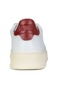 Sneaker bianco con tomaia in pelle liscia, un tallone in pelle rossa con logo impressa e una suola in gomma color crema.