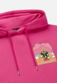 Roodachtige hoodie met een grafisch ontwerp van een personage dat een zwart schild vasthoudt, met een kleurrijke strand- en wolkenachtergrond in het ontwerp.