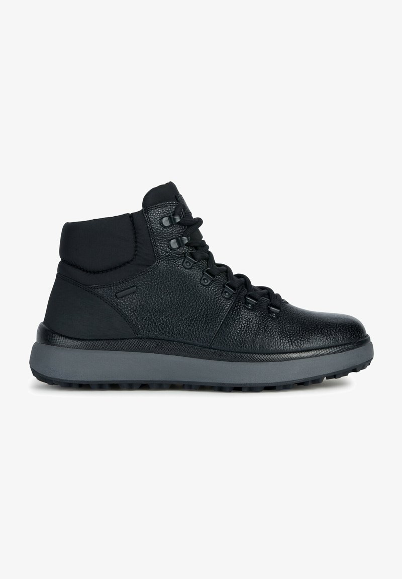 Baskets montantes en cuir noir avec cheville rembourrée, semelle épaisse grise, surface texturée et lacets noirs avec œillets métalliques.