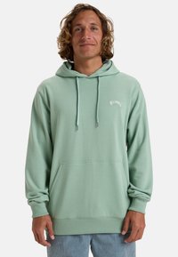 Mint green hoodie with a kangaroo pocket, drawstring hood, and ribbed cuffs. Features subtle “Billabong” logo on the chest. Soft fabric texture.