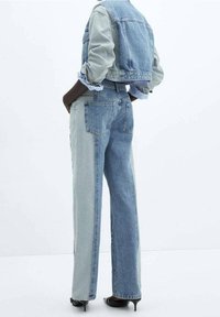Veste en denim bleu clair et foncé et jeans taille haute, coupe décontractée, avec des panneaux contrastants et un design de veste cropped.