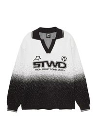 Langärmliger Polo-Pullover in Schwarz und Weiß mit einem verlaufenden gepunkteten Muster, "STWD"-Logo, Stern, Fußball und dem Text "AUS ANSTRENGUNG ENTSTEHT EINHEIT."