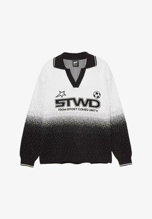 Langärmliger Polo-Pullover in Schwarz und Weiß mit einem verlaufenden gepunkteten Muster, "STWD"-Logo, Stern, Fußball und dem Text "AUS ANSTRENGUNG ENTSTEHT EINHEIT."