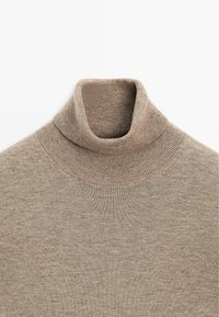 Beżowy sweter z golfem wykonany z miękkiego materiału dzianinowego, z wysokim, prążkowanym kołnierzem i gładką fakturą z delikatnymi wariacjami.