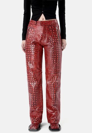 Pantalones de cuero sintético rojo con efecto cocodrilo y pierna recta, con bolsillos frontales con cremallera, combinados con un top negro corto abotonado.