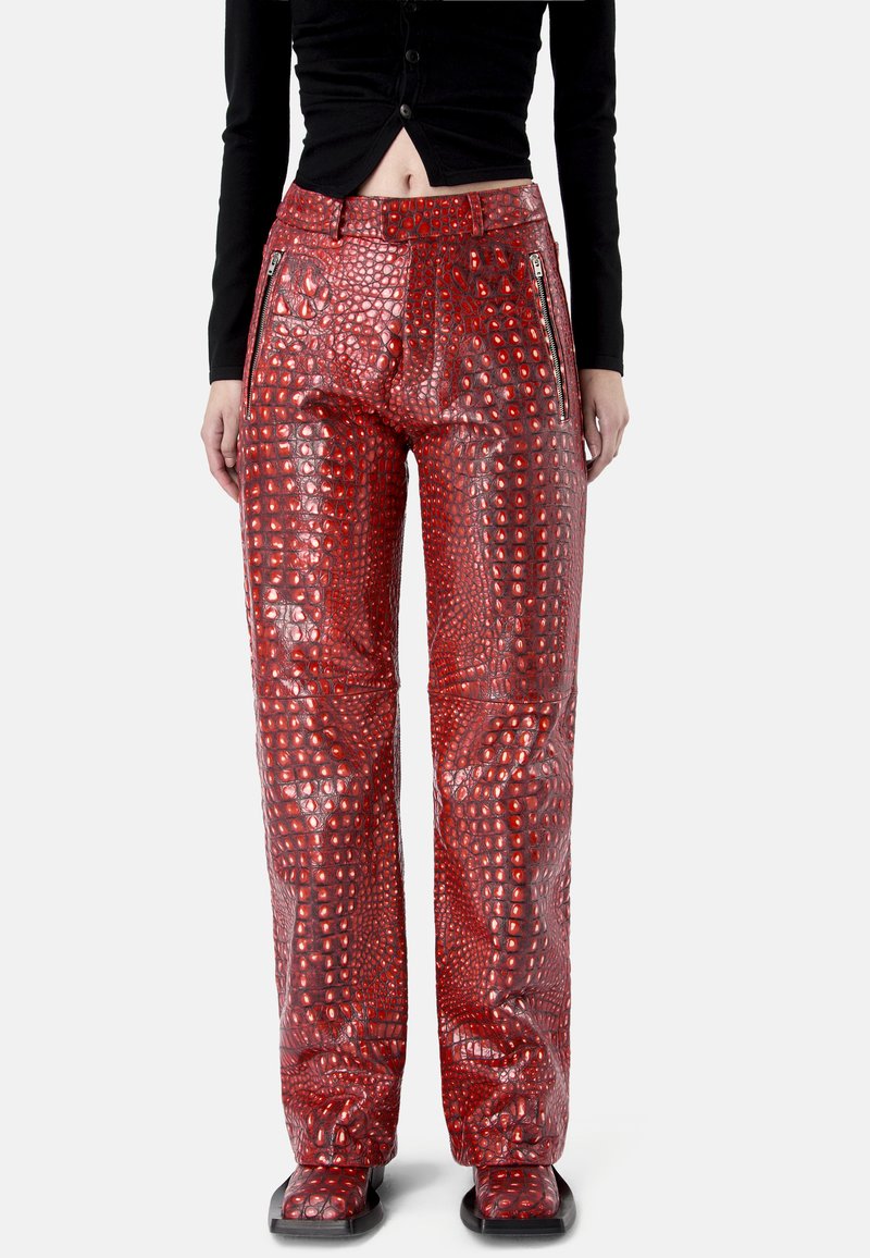 Pantalon droit rouge en cuir synthétique effet crocodile avec poches zippées à l'avant, porté avec un haut noir court boutonné.