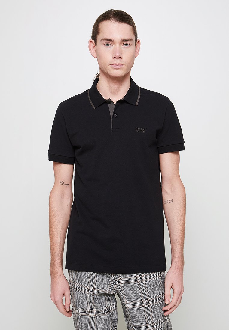 Polo noir à manches courtes avec un col brun contrastant, arborant le logo BOSS brodé sur la poitrine.