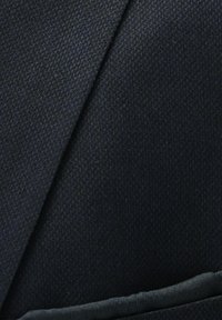 Close-up of dark navy blue textured suit jacket lapel and pocket detail.