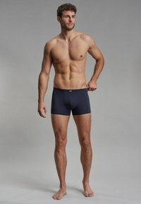 Dark blue boxer briefs made of stretch fabric, featuring a smooth texture and a branded elastic waistband, displayed on a male model.