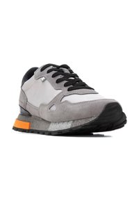Zapatilla de ante y malla gris con cordones negros, acento naranja en el talón y una suela de goma texturizada. Presenta una puntera redondeada y un collar acolchado.