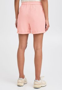 Rosa shorts med oppbrettede ermer og sidelommer, laget av et lett stoff. Elastisk midje og minimale sømdetaljer.