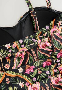 Robe florale avec un fond noir orné de fleurs et de feuilles colorées et détaillées ; comprend des bretelles ajustables et un design de tissu froncé.