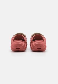 Red rubber clogs with a textured surface, open back design, and ventilation holes. The interior is beige.
