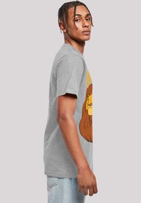 Siva pamučna majica s grafikom crtanog lava u smešnom i žutom. Okrugli izrez, kratki rukavi, opušten fit.