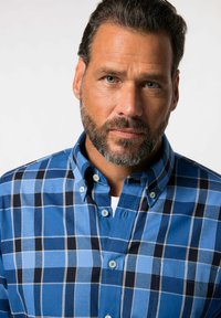 Camisa de botones en tonos azules, con un patrón de cuadros en diferentes matices, la textura del tejido es suave, incluye un cuello y cierre de botones.