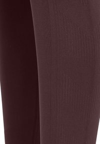 Bordeaux legging met een gladde textuur en een geribbeld patroon, voorzien van versterkte naden aan de zijkanten voor extra duurzaamheid.