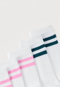 Chaussettes blanches avec deux bandes horizontales en haut : une paire a des bandes roses, l'autre paire a des bandes vert foncé.