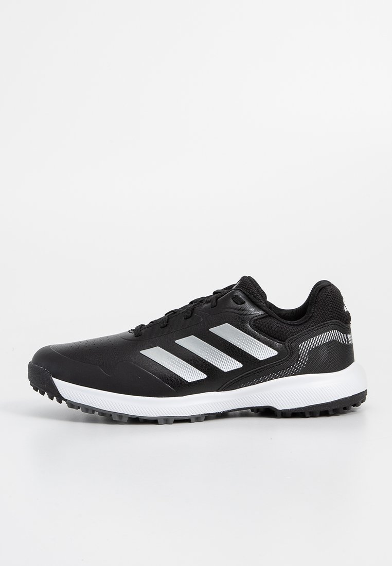Chaussure de sport noire avec des accents argentés et trois bandes. Présente un dessus texturé, un système de laçage et une semelle extérieure blanche avec une bonne traction.