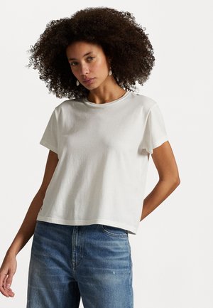 White cotton t-shirt with a rounded neck, short sleeves, and a relaxed fit, paired with blue denim jeans. Smooth fabric texture, simple design.