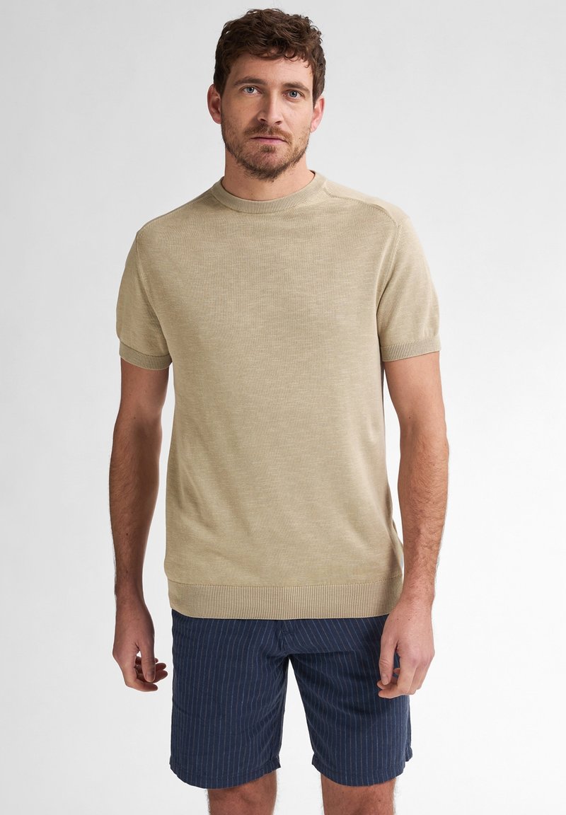 Beige gestrickter Kurzarmpullover mit Rundhalsausschnitt und gerippten Bündchen, kombiniert mit navy-blauen gestreiften Shorts. Glatte Textur, einheitliche Farbe, lässige Passform.