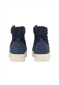 Botas de tobillo azul marino con un suave collar acolchado, material sintético liso, suela de goma textura crema y un logotipo emblema en el talón.