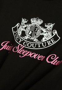 Zwart T-shirt met een witte afbeelding van een kroontje en twee honden, en roze tekst in een cursief lettertype met de woorden "Juicy Sleepover Club".
