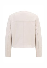 Kurzärmlige, cropped Jacke aus hellbeigem Wildleder mit glatter Textur, die ein minimalistisches Design und kontrastierende Nahtdetails aufweist.