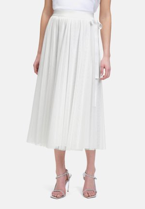 Weiße, plissierte Short aus leichtem Stoff, mit hoher Taille und seitlichem Bindeband, kombiniert mit metallischen, gegurteten High-Heels.