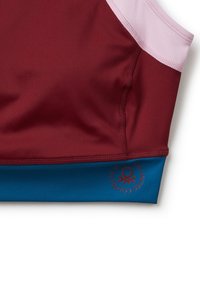 Sportbeha met een bordeauxrode bovenkant, lichtroze banden en een blauwe onderkant met geprinte logo. Glad, rekbaar materiaal met platte naden.