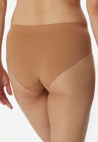 Beige katoenen boxershort met een brede elastische tailleband, een gladde textuur en een naadloos ontwerp, met een bescheiden snit en zonder zichtbare hardware.