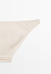Parte inferiore di bikini in misto cotone beige con una texture liscia, vita elasticizzata e design minimalista. Senza motivi né dettagli in metallo.