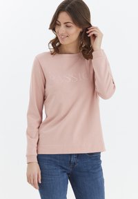 Sudadera de manga larga en color rosa claro, confeccionada con tela suave, que presenta la palabra "PASIÓN" en un diseño texturizado a lo largo del pecho.