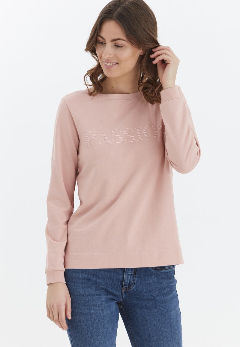 Sudadera de manga larga en color rosa claro, confeccionada con tela suave, que presenta la palabra "PASIÓN" en un diseño texturizado a lo largo del pecho.