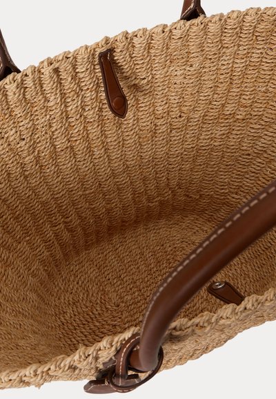 Fonott szalmából készült válltáska barna bőr fogantyúkkal és díszítéssel, felülről nyitott állapotban látható, kiemelve a varrást és a fonott textúrát.
