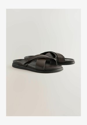 Mustad mustad nahast sandaalid, millel on kattuvad rihmad, lame tall ja ilma nähtava riistvara või kaunistusteta. Siledat tekstuuri ja minimalistlikku disaini.