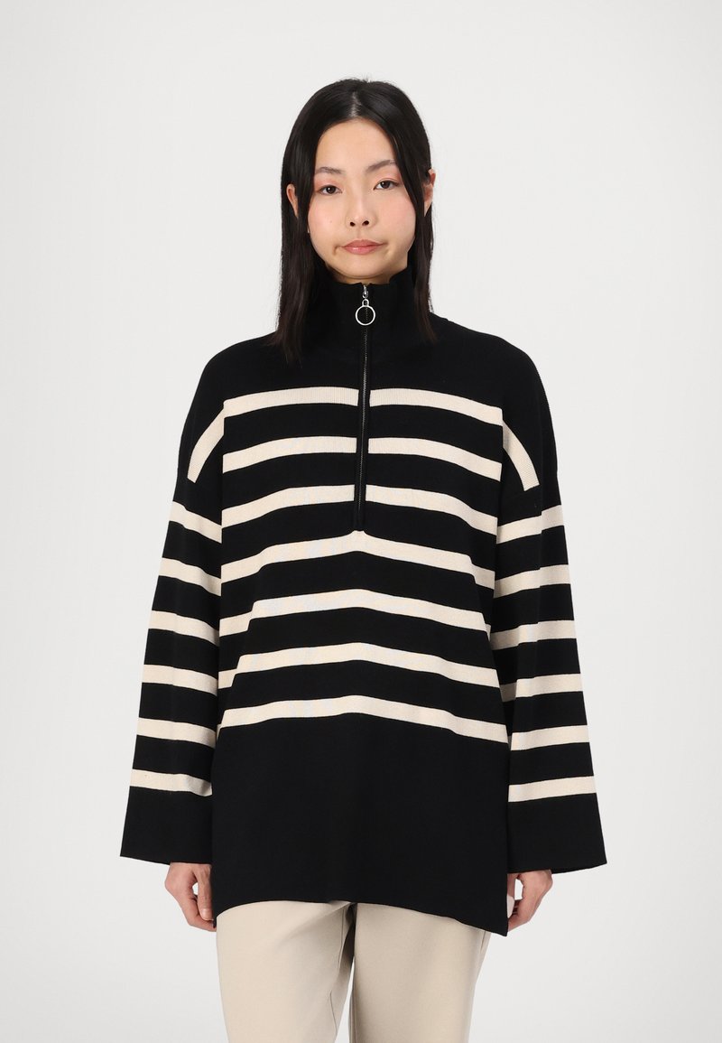 Black and cream striped pullover sweater with a high collar and quarter-zip front. Made of soft fabric, featuring long sleeves and a relaxed fit.