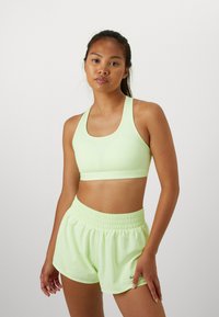 Soutien-gorge de sport Nike vert clair et shorts décontractés assortis avec une taille élastique. Texture lisse et détails de conception minimaux, avec des accents de logo.