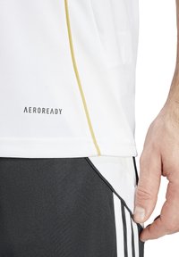 Witte Aeroready sportshirt met een gouden accentlijn. Zwarte shorts met witte strepen. Gladde stof, casual fit en zichtbaar logo.