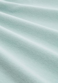 Miękka, jasnoniebieska tkanina z delikatnymi fałdami podkreślającymi jej gładką teksturę i subtelne cieniowanie.