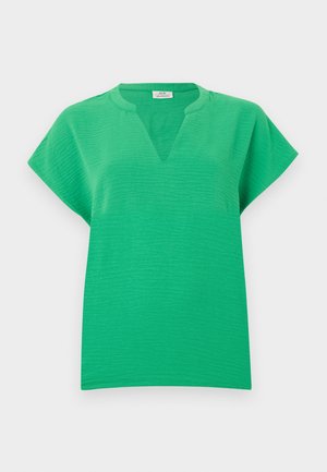 Élénk zöld rövid ujjú blúz texturált anyagból, V-alakú nyakkivágással, tiszta fehér háttéren bemutatva.