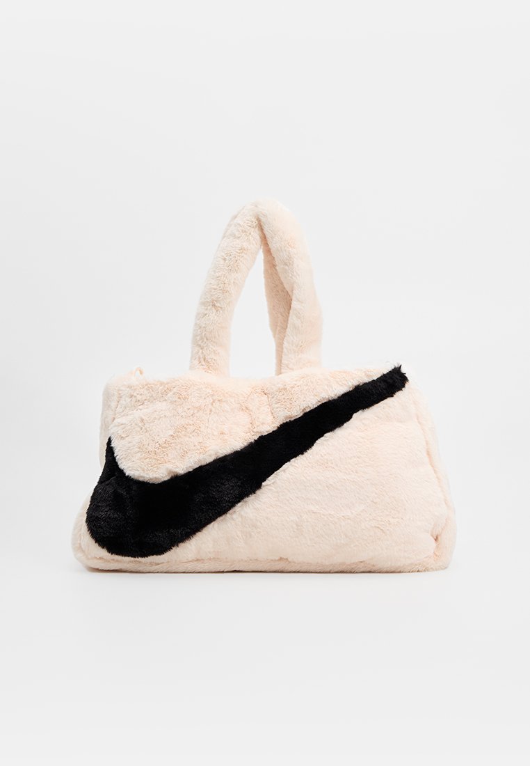Borsa in faux fur rosa chiaro con un accento in peluche nero a forma di logo, dotata di due manici arrotondati e una superficie morbida e testurizzata.