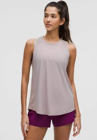 Débardeur de sport gris clair avec une texture lisse, col arrondi et accents transparents aux épaules, associé à un short violet foncé.