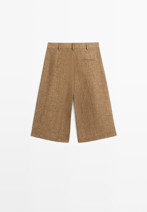 Hnědé široké šortky délky po kolena s poutky na opasek a jedním zadním klopu, zobrazené na bílém pozadí.