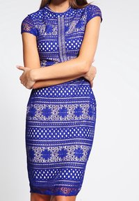 Royal blue lace dress with short sleeves, featuring a diamond pattern and floral accents. Form-fitting design with a knee-length hem.