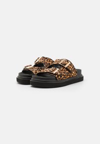 Leopard print slide sandals with two adjustable straps, black rubber soles, and metallic accents for fastening. Soft fabric texture.