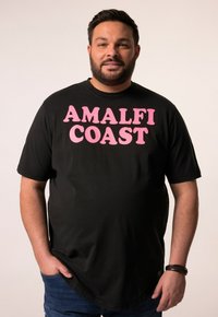 Camiseta negra de manga corta con gran texto rosa que dice "COSTA DE AMALFI". Tela suave con un cuello redondo y un ajuste relajado.